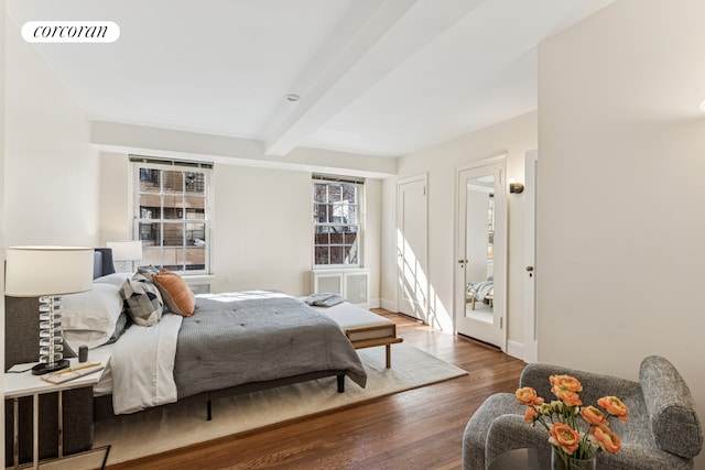 bedroom featuring baseboards, wood finished floors, visible vents, and beam ceiling