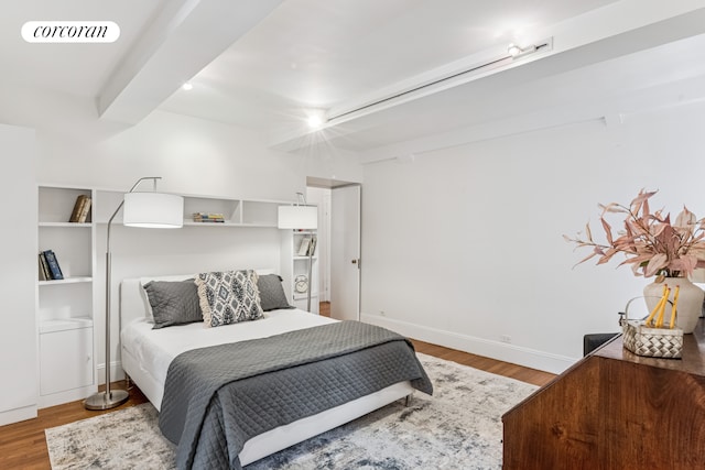 bedroom with baseboards, wood finished floors, visible vents, and beam ceiling