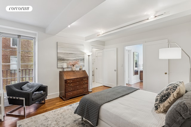 bedroom with baseboards, wood finished floors, visible vents, and beam ceiling