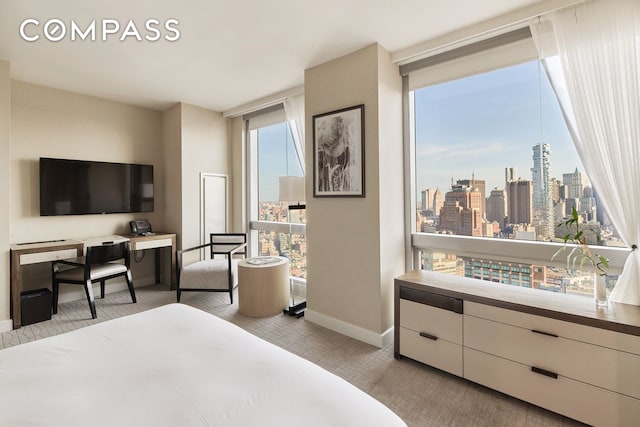 bedroom with floor to ceiling windows, a view of city, and baseboards