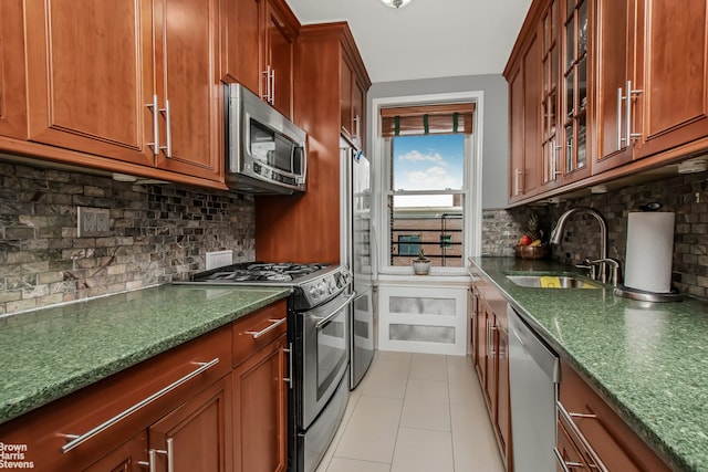 kitchen with dark stone counters, tasteful backsplash, a sink, glass insert cabinets, and stainless steel appliances