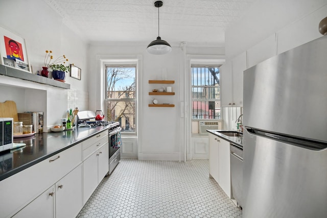 kitchen with appliances with stainless steel finishes, a healthy amount of sunlight, a sink, and white cabinets