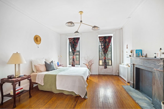 bedroom featuring light wood-type flooring, a fireplace, and radiator heating unit