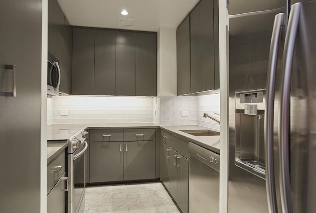 kitchen with recessed lighting, gray cabinetry, stainless steel appliances, a sink, and decorative backsplash