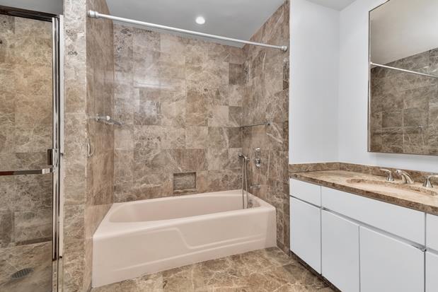 bathroom featuring washtub / shower combination and vanity