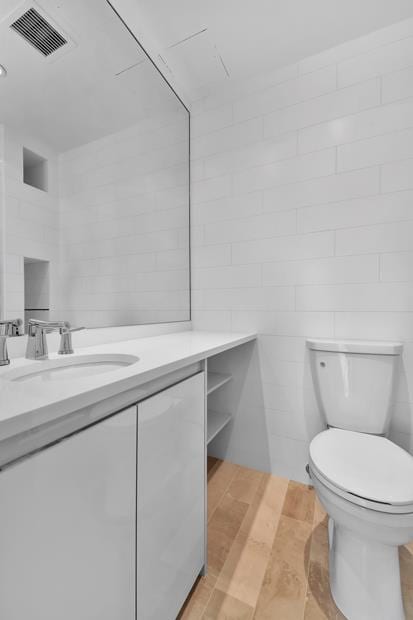 bathroom with visible vents, vanity, toilet, and wood finished floors