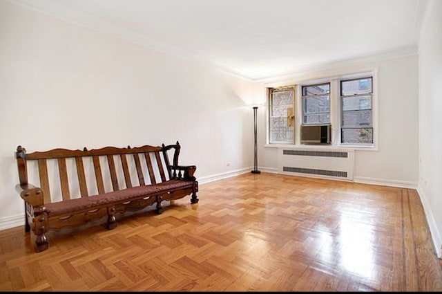 living area with radiator heating unit, ornamental molding, baseboards, and cooling unit