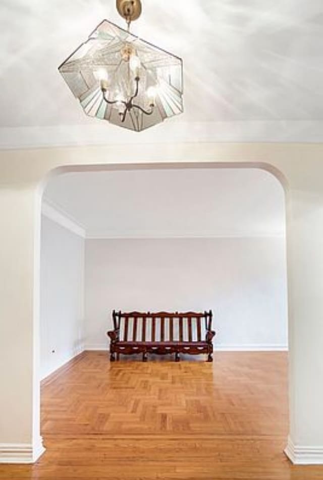 bonus room featuring arched walkways, baseboards, and a chandelier