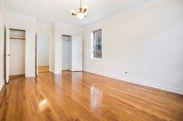 unfurnished bedroom featuring multiple closets, a chandelier, light wood-type flooring, baseboards, and crown molding