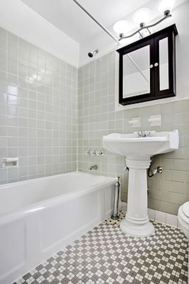 bathroom featuring tile walls, shower / washtub combination, toilet, and tile patterned floors