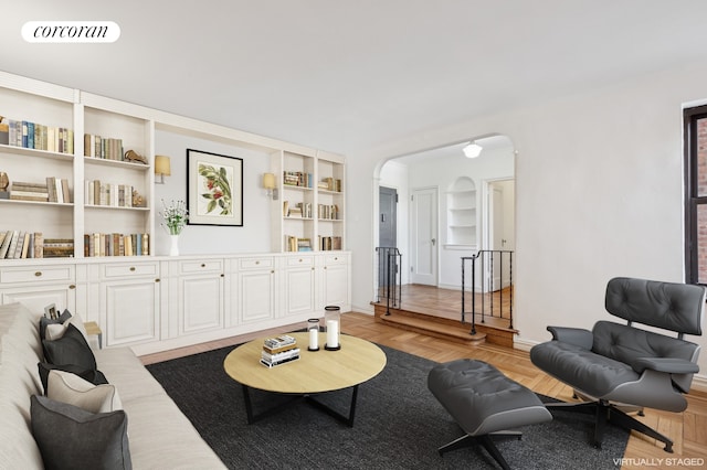 living area featuring visible vents, arched walkways, baseboards, and built in shelves