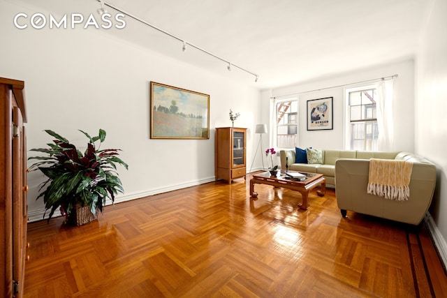 living area featuring track lighting, baseboards, and a baseboard heating unit