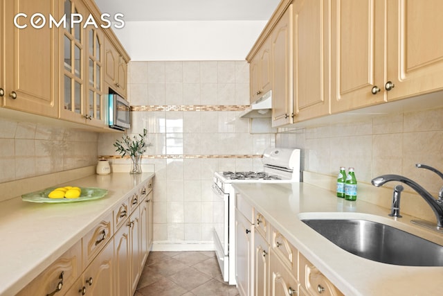 kitchen featuring white gas range, stainless steel microwave, light countertops, and a sink