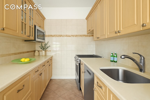 kitchen featuring decorative backsplash, appliances with stainless steel finishes, a sink, light countertops, and light tile patterned flooring
