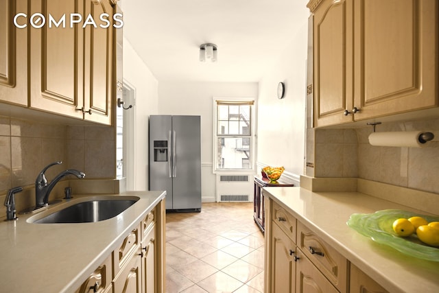 kitchen featuring stainless steel fridge with ice dispenser, light countertops, radiator heating unit, light tile patterned floors, and a sink