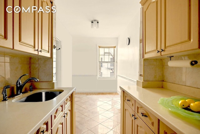 kitchen featuring a sink, light countertops, decorative backsplash, and baseboards