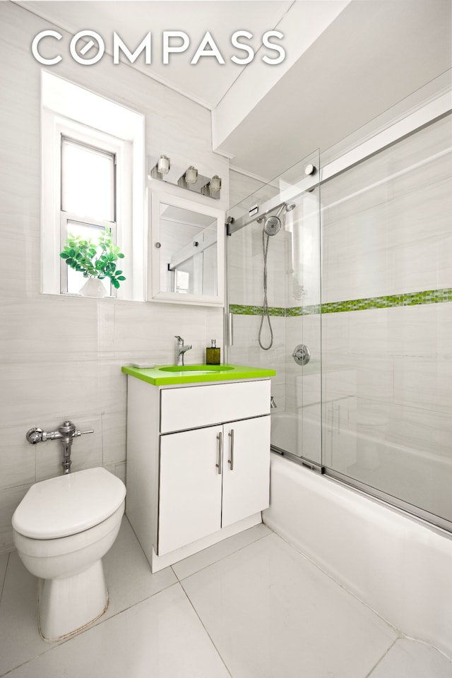 bathroom featuring tile walls, tile patterned flooring, vanity, bath / shower combo with glass door, and toilet