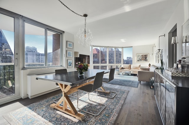 dining area featuring a city view, an inviting chandelier, plenty of natural light, and dark wood-style flooring