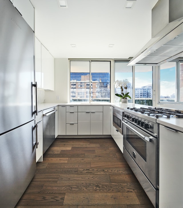 kitchen featuring light countertops, wall chimney exhaust hood, white cabinetry, and stainless steel appliances