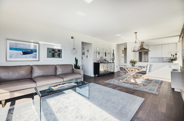 living room with baseboards, a notable chandelier, and dark wood-type flooring