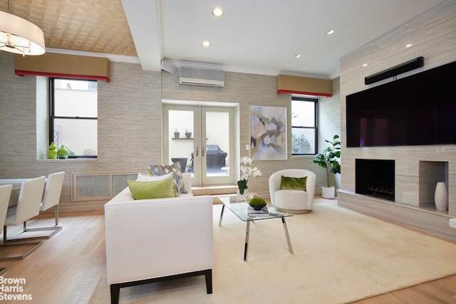 living room featuring a fireplace, wood finished floors, an AC wall unit, french doors, and crown molding