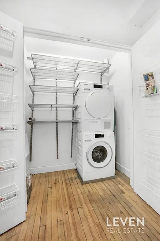 clothes washing area featuring laundry area, stacked washer and dryer, and light wood finished floors