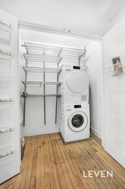 laundry area featuring light wood-style floors, stacked washer / dryer, and laundry area