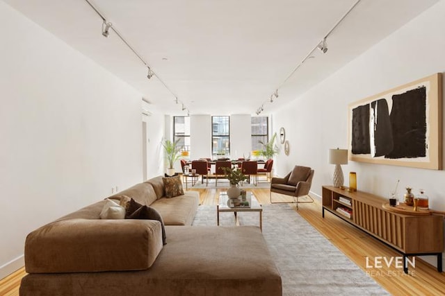 living area featuring track lighting, light wood-type flooring, and baseboards