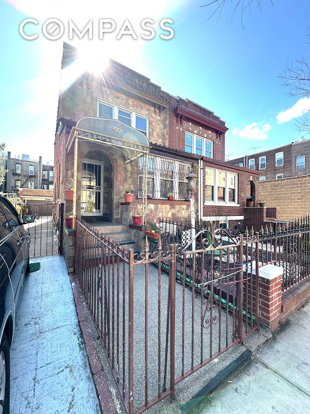 view of front of house with a fenced front yard, stone siding, and a gate