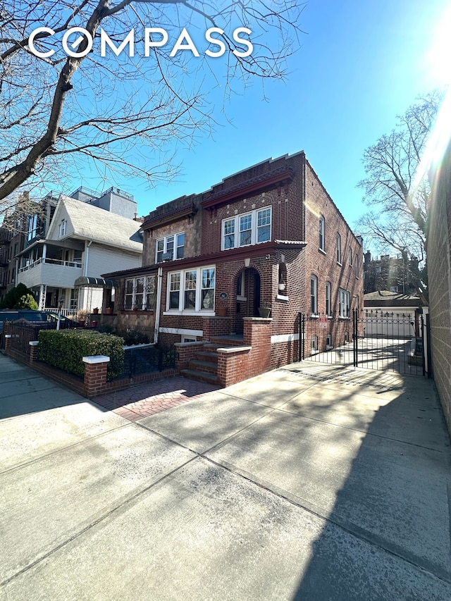 view of front facade with fence, brick siding, and a gate