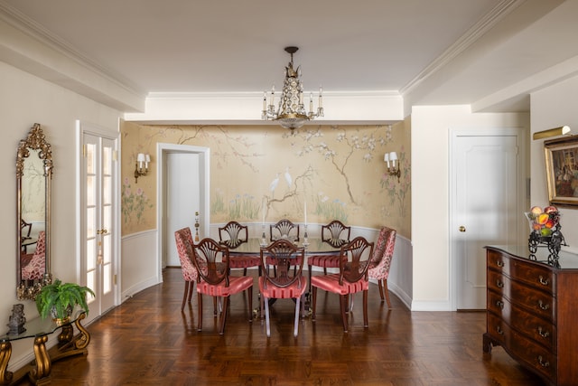 dining area with a wainscoted wall, a notable chandelier, ornamental molding, and wallpapered walls