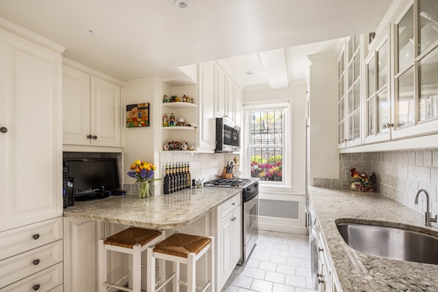 kitchen featuring open shelves, light stone counters, appliances with stainless steel finishes, and a sink