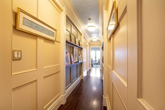 hall featuring crown molding, dark wood finished floors, and a decorative wall