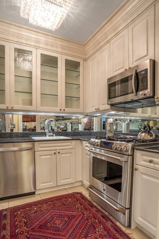 kitchen featuring light tile patterned flooring, stainless steel appliances, a sink, dark countertops, and glass insert cabinets