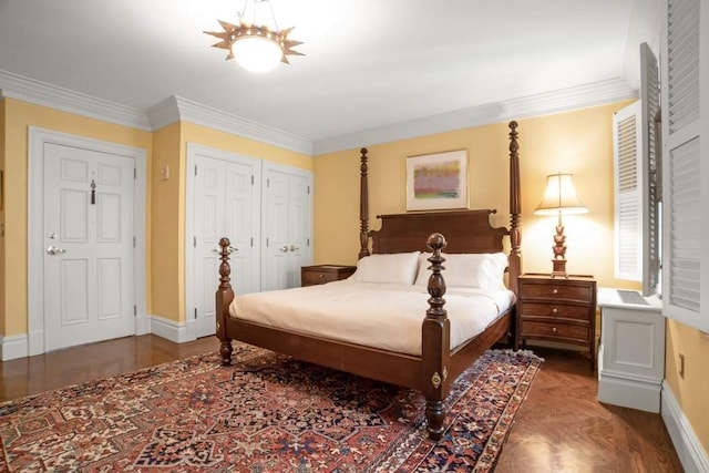 bedroom with ornamental molding, two closets, and baseboards