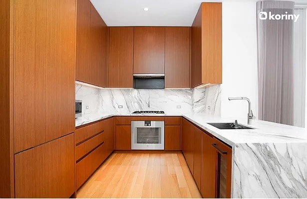 kitchen with oven, a sink, light wood-type flooring, tasteful backsplash, and brown cabinetry