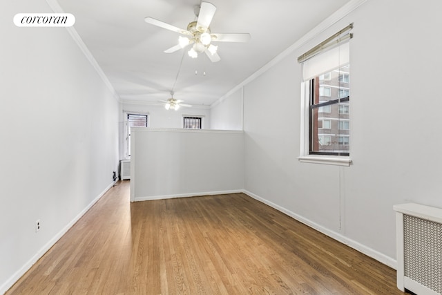 spare room with crown molding, wood finished floors, ceiling fan, and baseboards