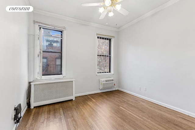 unfurnished room with radiator, a wall mounted air conditioner, wood finished floors, healthy amount of natural light, and crown molding