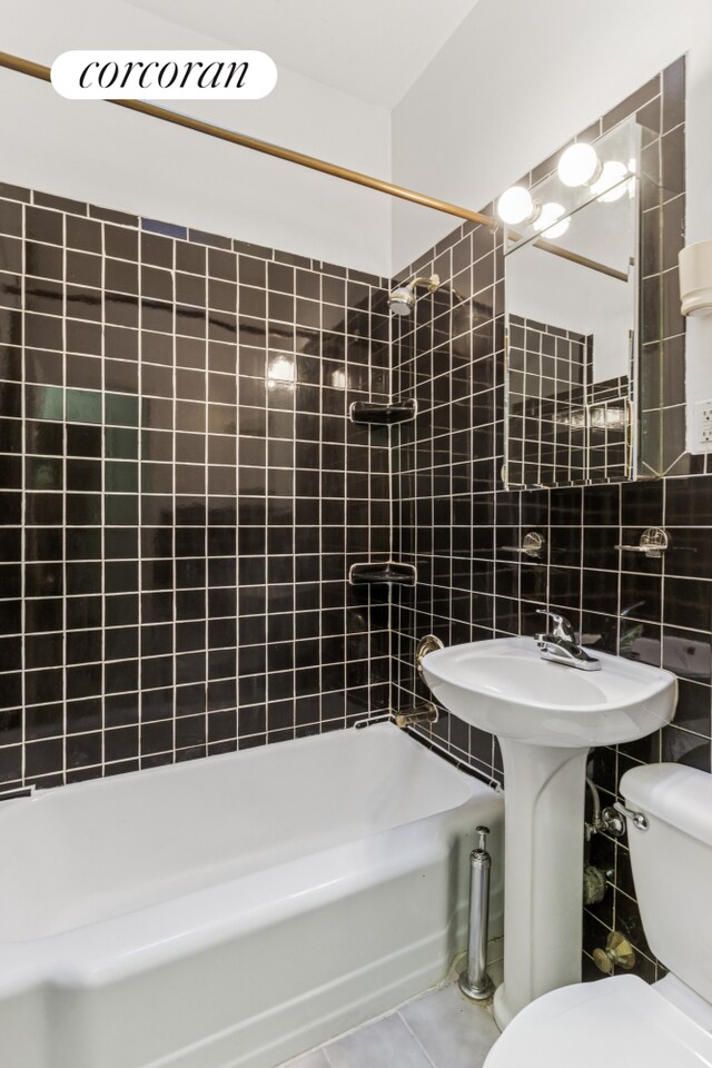 220 E 87th St Unit 5B, New York City, NY 10128 - bathroom with toilet, tile walls, washtub / shower combination, tile patterned flooring, and a sink