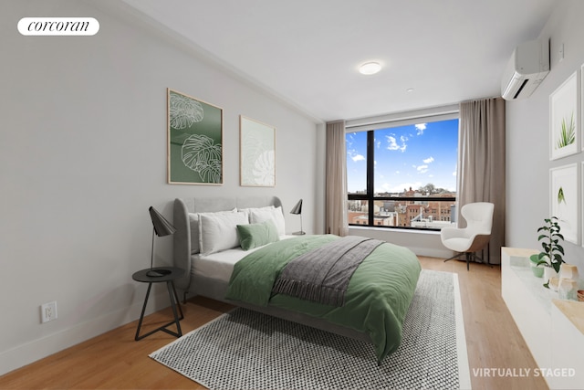 bedroom with light wood finished floors, a wall mounted air conditioner, visible vents, and baseboards