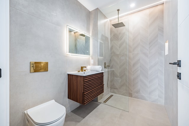 full bathroom featuring toilet, tile walls, vanity, tile patterned floors, and walk in shower