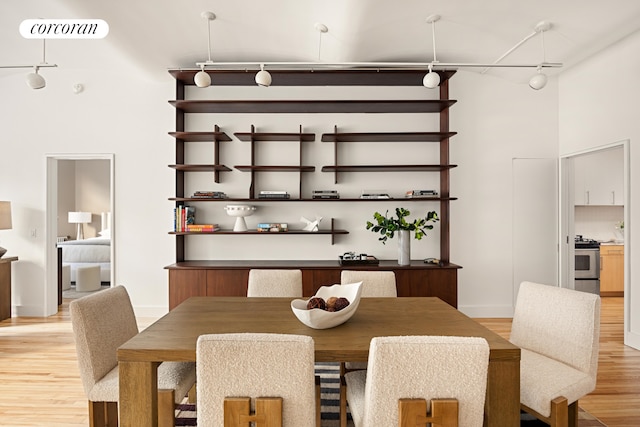 dining area with track lighting, a towering ceiling, visible vents, and light wood-style floors