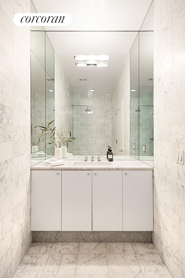 bathroom featuring marble finish floor, tiled shower, and vanity