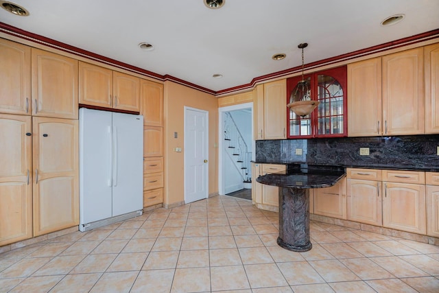 kitchen with light tile patterned flooring, backsplash, dark stone counters, and freestanding refrigerator