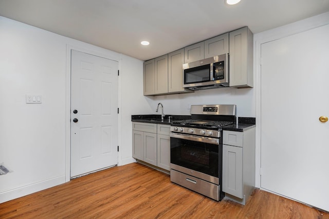 kitchen with a sink, stainless steel appliances, light wood-style floors, and gray cabinetry