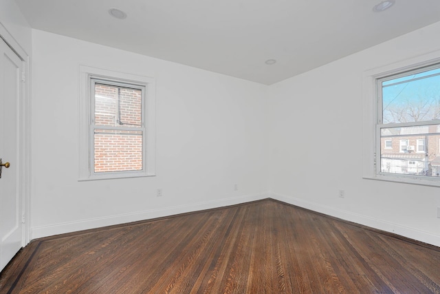 unfurnished room with baseboards and dark wood-style flooring