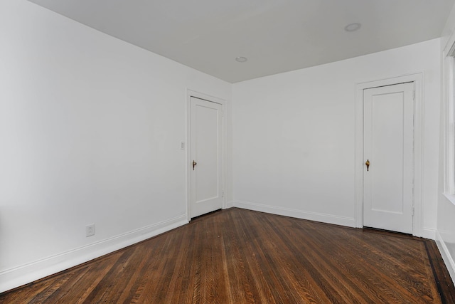 unfurnished room featuring baseboards and dark wood-type flooring