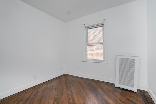 unfurnished room featuring baseboards, radiator, and dark wood-style flooring