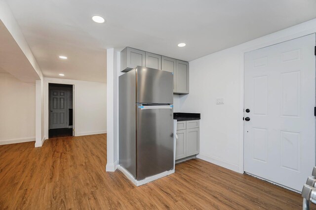 kitchen with recessed lighting, wood finished floors, freestanding refrigerator, and gray cabinetry