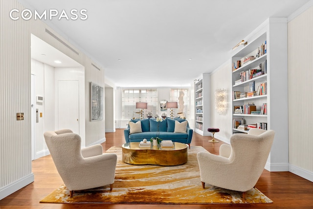 living area featuring baseboards, built in shelves, and wood finished floors
